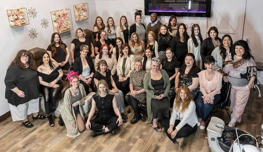 Group of smiling people posing in a room with floral artwork on the walls.