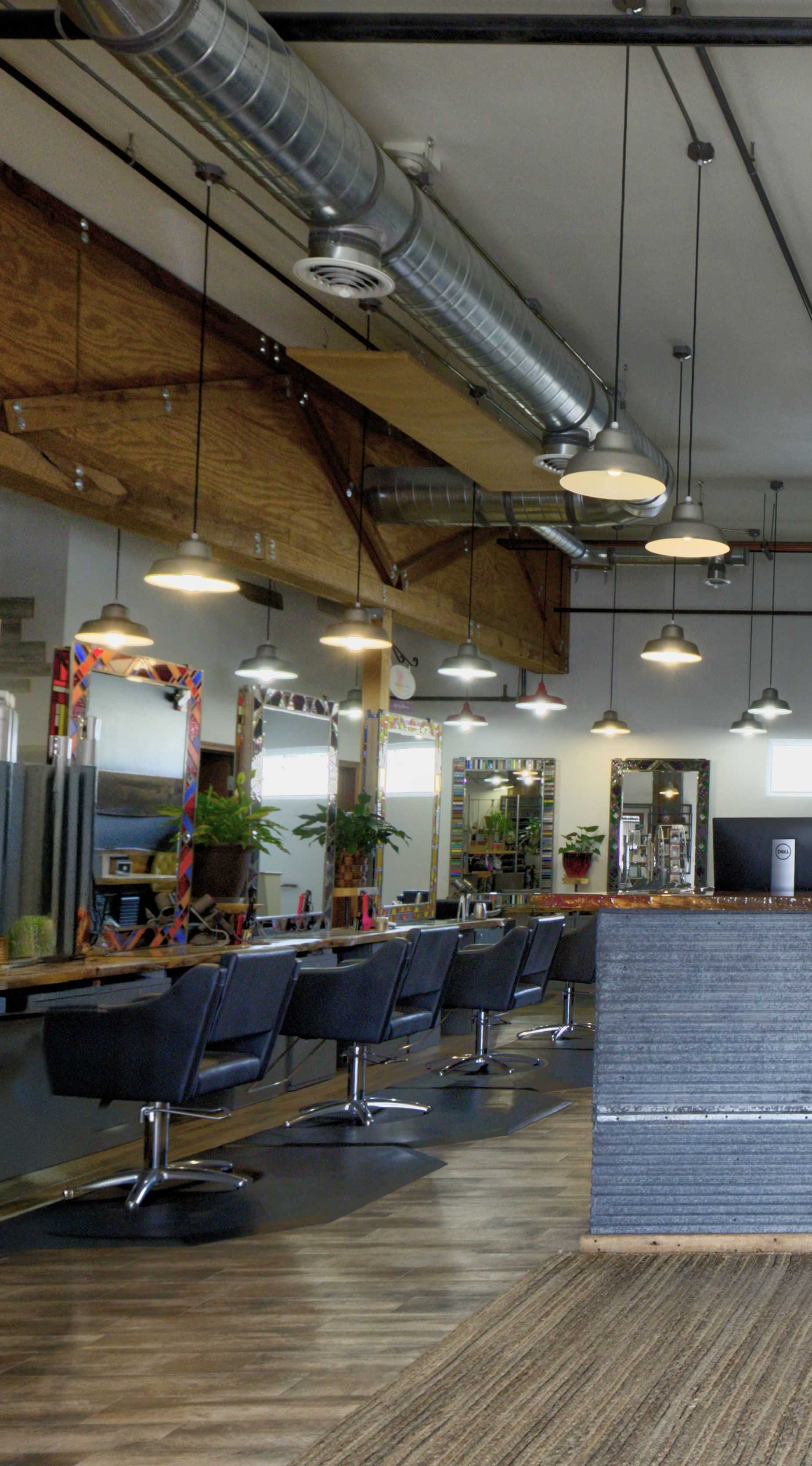 Modern hair salon interior with empty styling stations and industrial lighting.