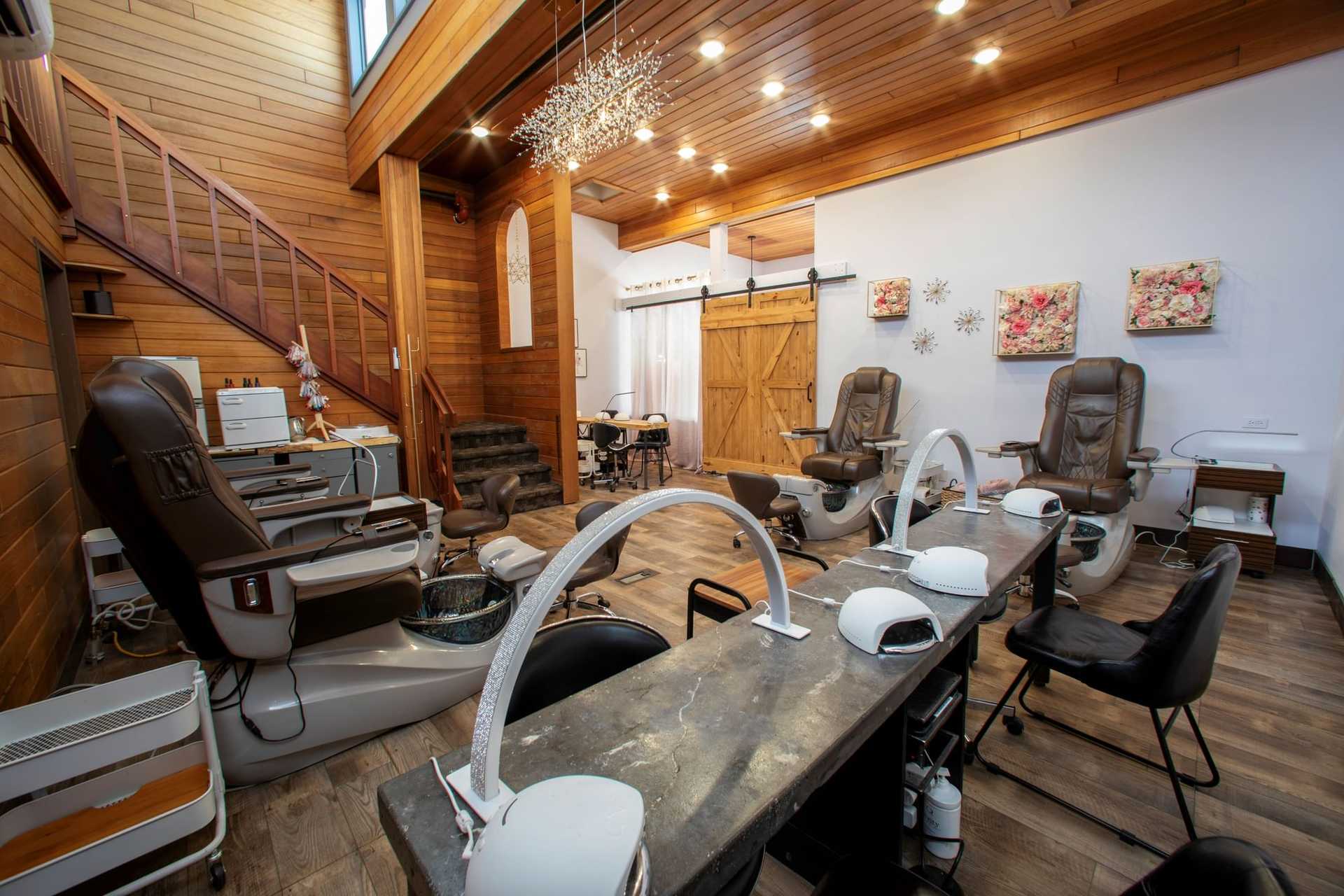 Nail salon interior with pedicure chairs, manicure stations, and wooden decor.